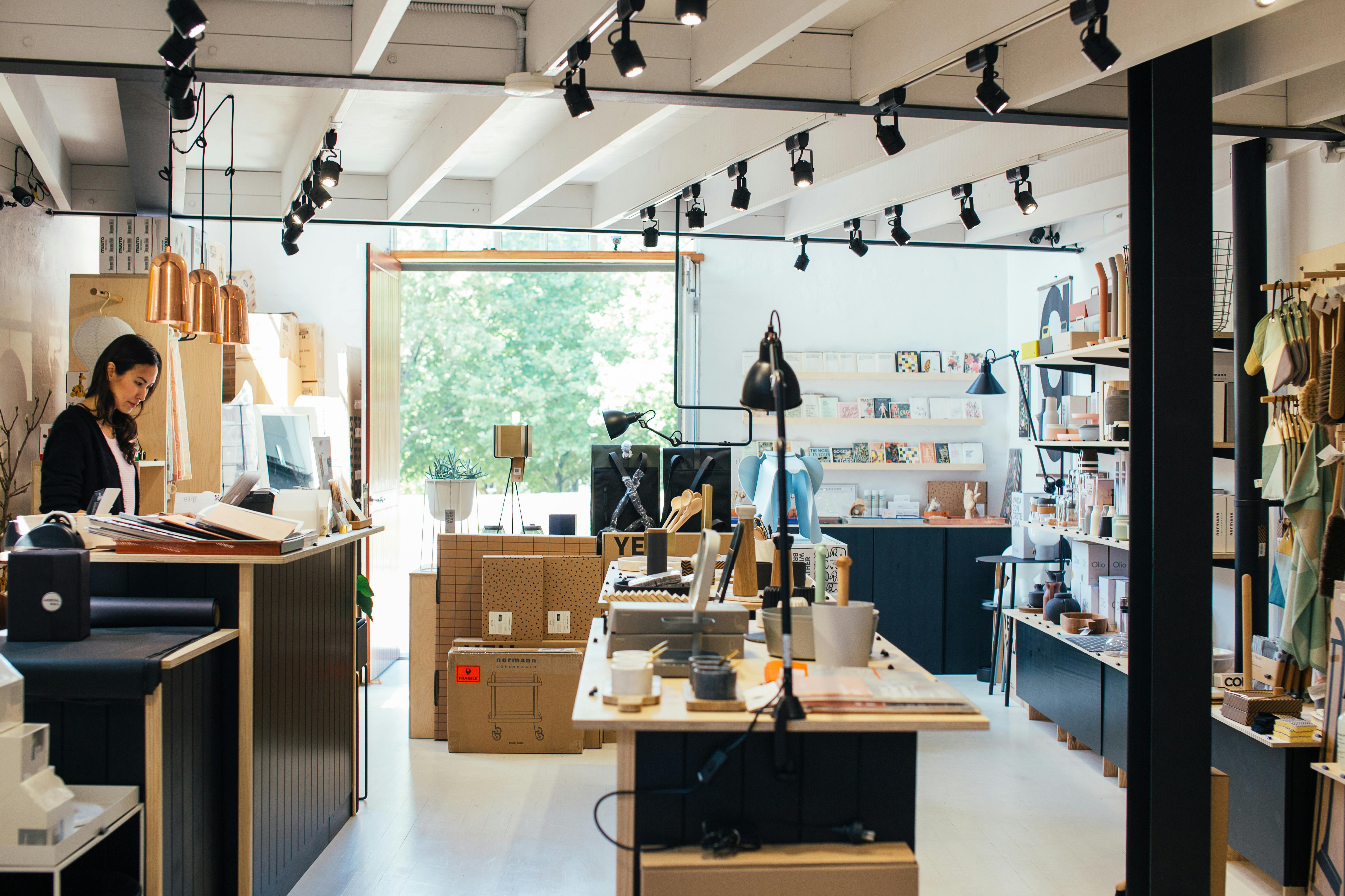 Young woman employee standing at counter in creative gift shop