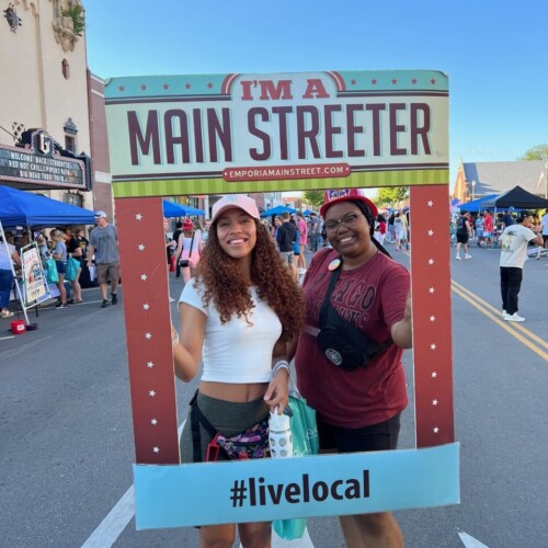 Two community members in Emporia Kansas pose with a sign saying "I'm a Main Streeter"