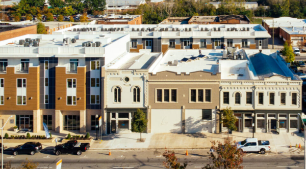 Aerial view of a street with commercial and upper story residential buildings.