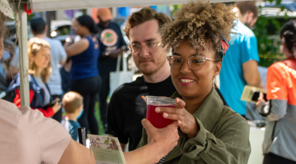 A vendor hands a beverage to a customer.