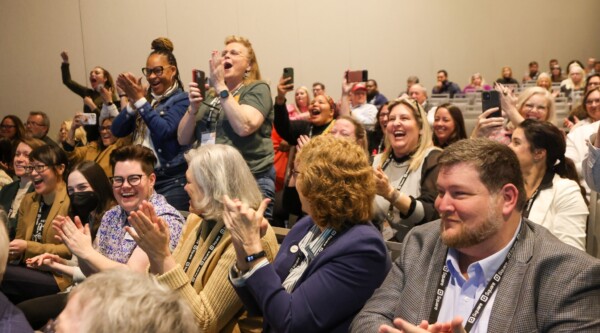 Conference attendees applaud enthusiastically.