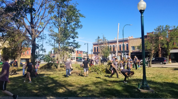 Volunteers in a downtown park cleaning up fallen tree limbs and other debris