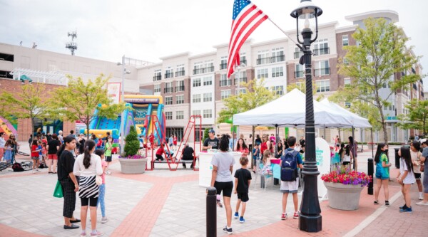 Street fair in a town plaza with vendor booths and an inflatable slide in Metuchen, New Jersey