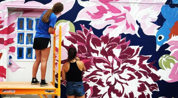 Two people working on a large mural