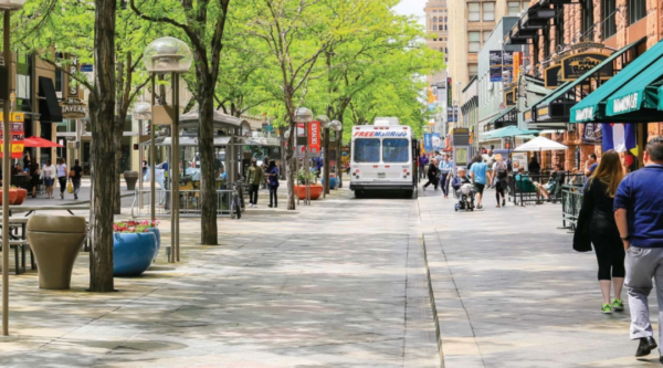 People walking along a tree-lined downtown street