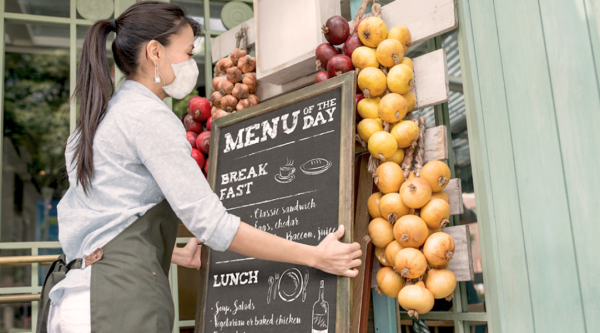 Woman hanging a chalkboard menu outside a small business