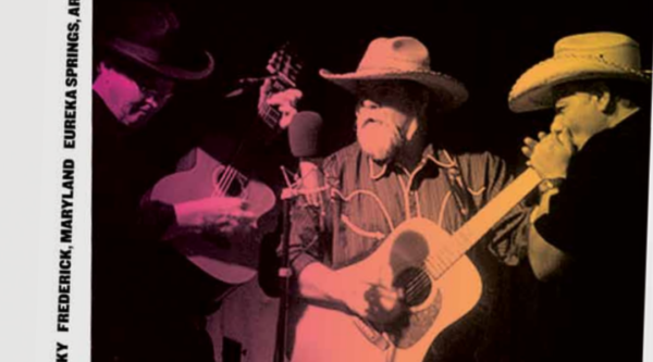 Three men performing on stage wearing country music attire