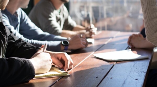 People around a table taking notes during a meeting