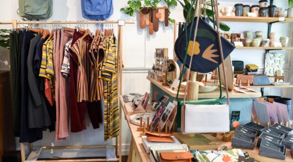 A retail shop with a rack of clothing and shelves of mugs and other items