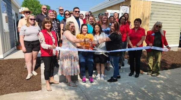 A large group of people posing at a ribbon cutting to open the micro retail space