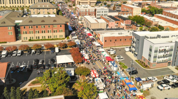 Aerial photograph of a historic downtown during a festival event with people and vendor tents lining the main street