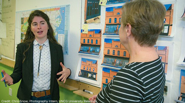 Two women speak in a classroom