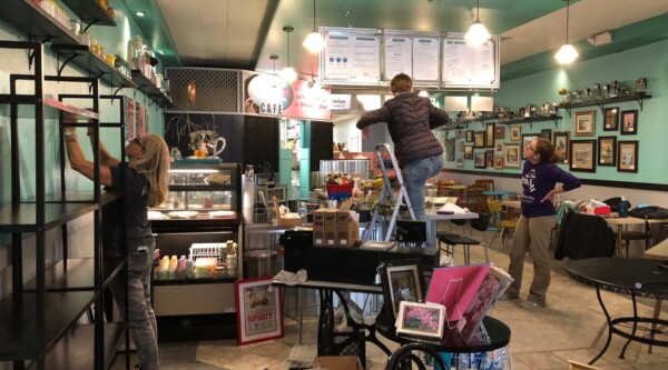 Group of three women set up a retail display in a small cafe.