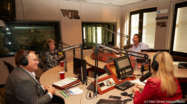 Group of four people sitting in podcast recording booth