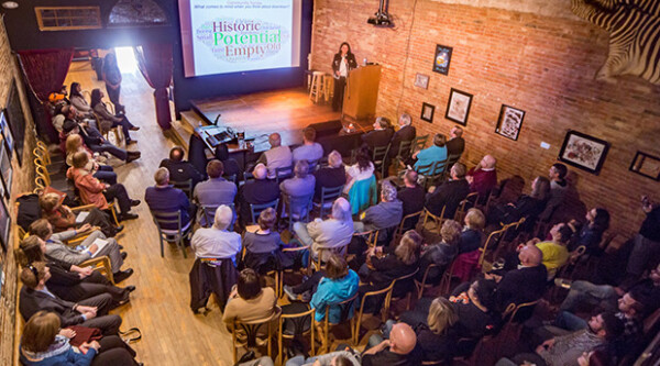 Group of people gathered in a classroom listening to a speaker in front of a PowerPoint screen.