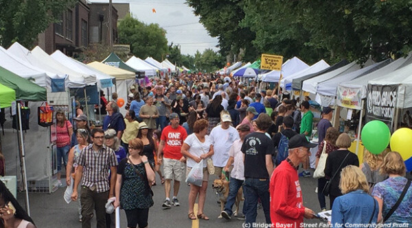 Group of people walking through outdoor farmers market.