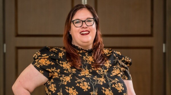 Photo of smiling woman with red hair wearing glasses and floral shirt