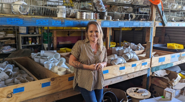 A young woman standing in a room with plumbing components.