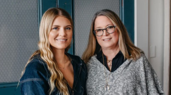 Photo of two smiling women in front of a blue door.