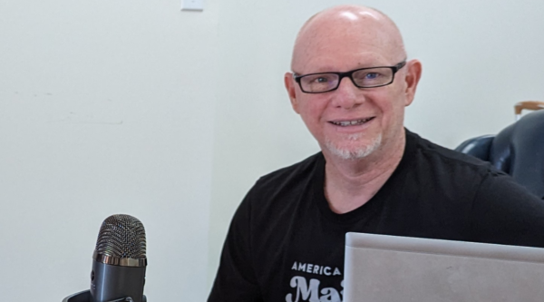 Photo of Chief Program Officer Matt Wagner in front of a podcast microphone and laptop.