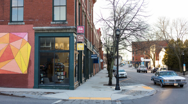 Tree lined Main Street with a corner cafe and a mural on a brick will