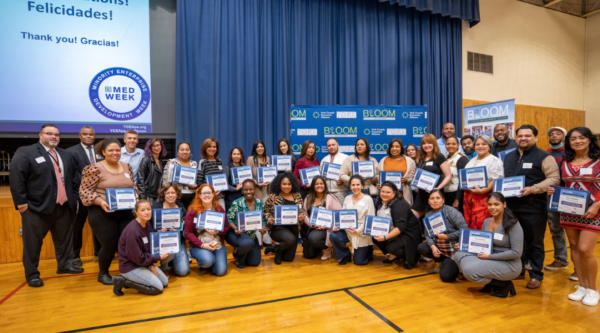 Graduates of the BLOOM center post on a basketball court holding their certificates