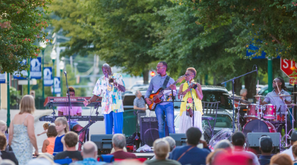 A band performs on an outdoor stage in front of a large crowd