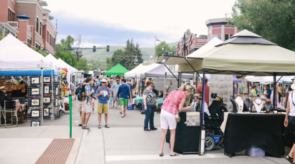 Outdoor farmer's market with people shopping at vendor stalls