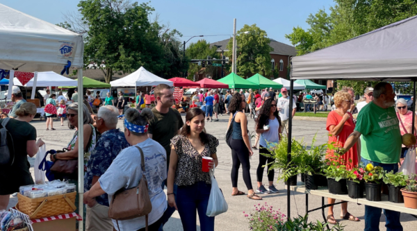 People shopping at an outdoor farmer's market on a sunny day